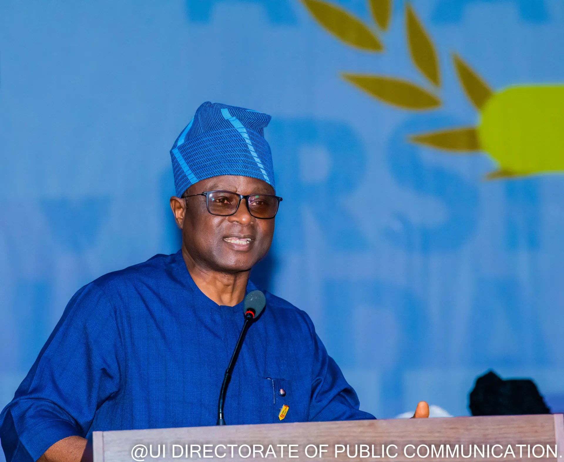 A speaker in blue traditional attire standing at the forum lectern.