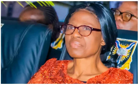 A forum guest wearing glasses and an orange outfit seated in the audience.