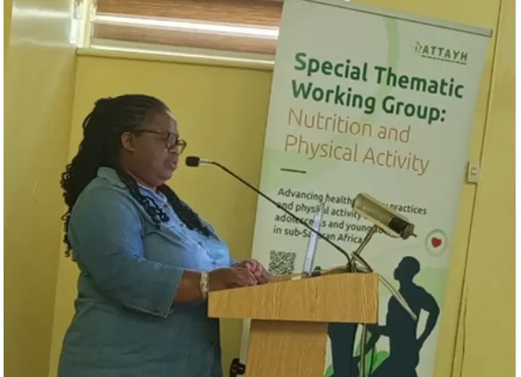 A workshop presenter in blue speaking beside a thematic working group banner.