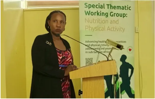 A workshop presenter at a lectern beside a nutrition and physical activity banner.