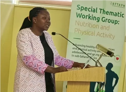 A workshop presenter in a patterned outfit beside a thematic working group banner.
